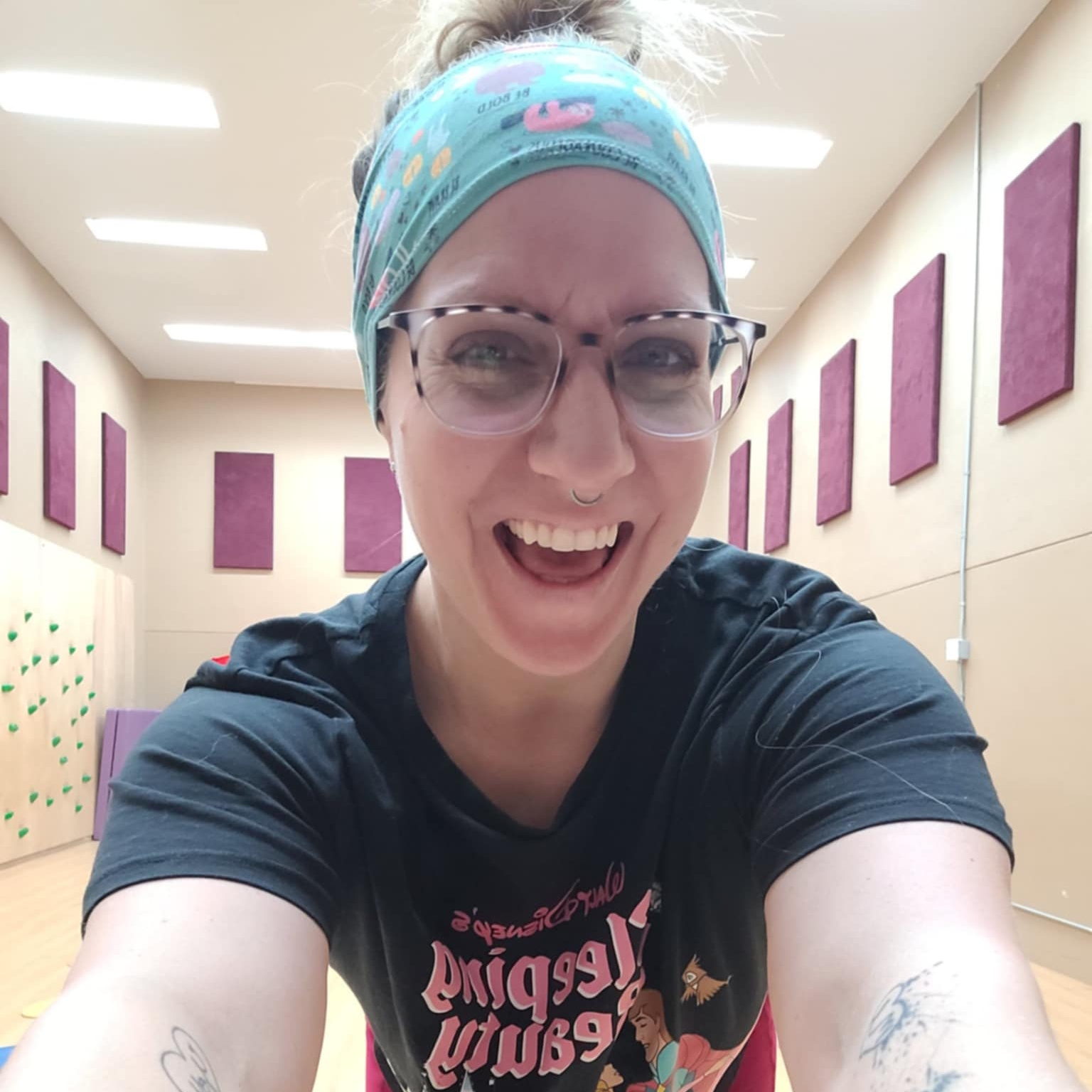 A woman wearing glasses is smiling and giving a peace sign