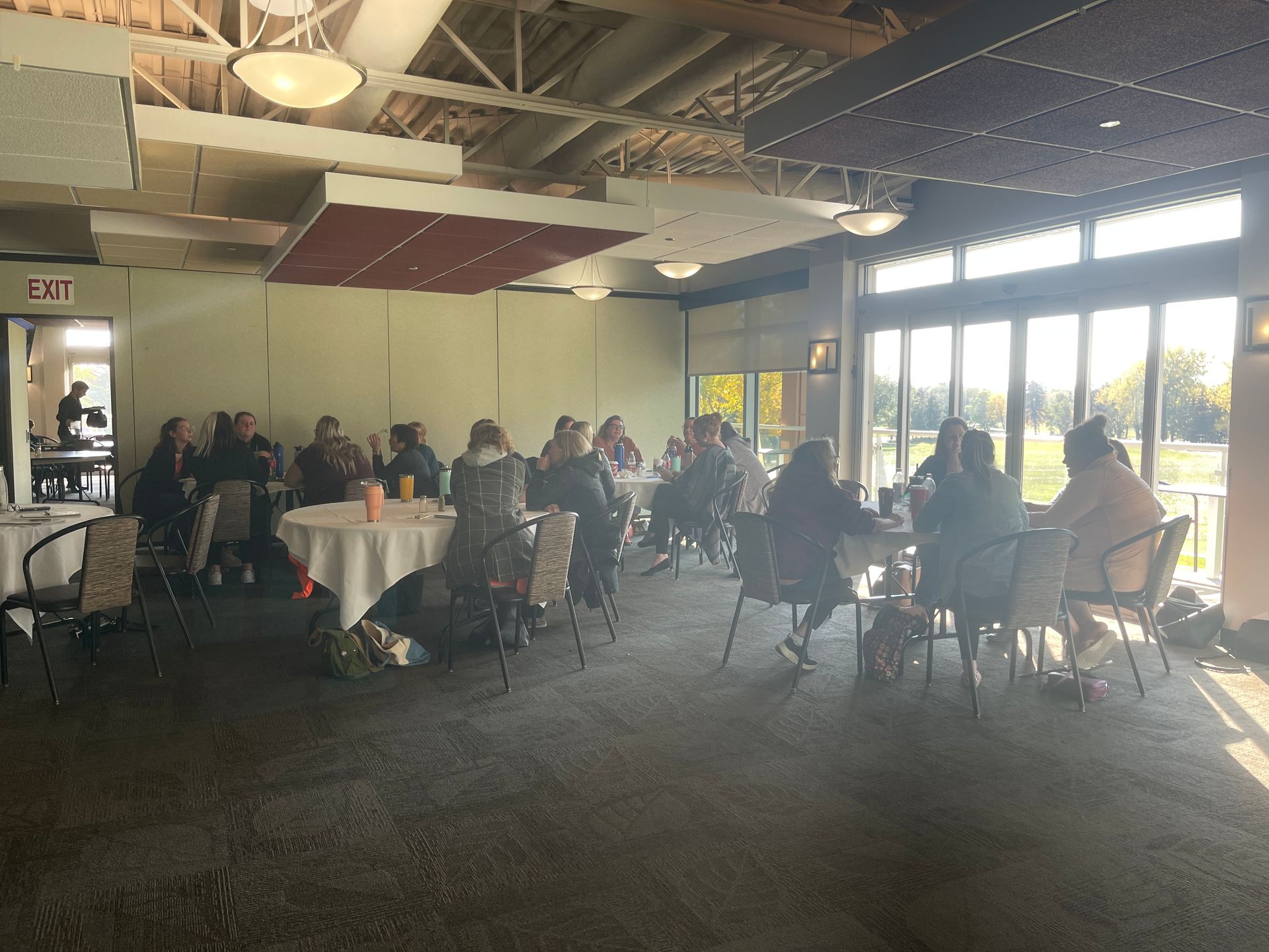 A group of people are sitting at tables in a large room.