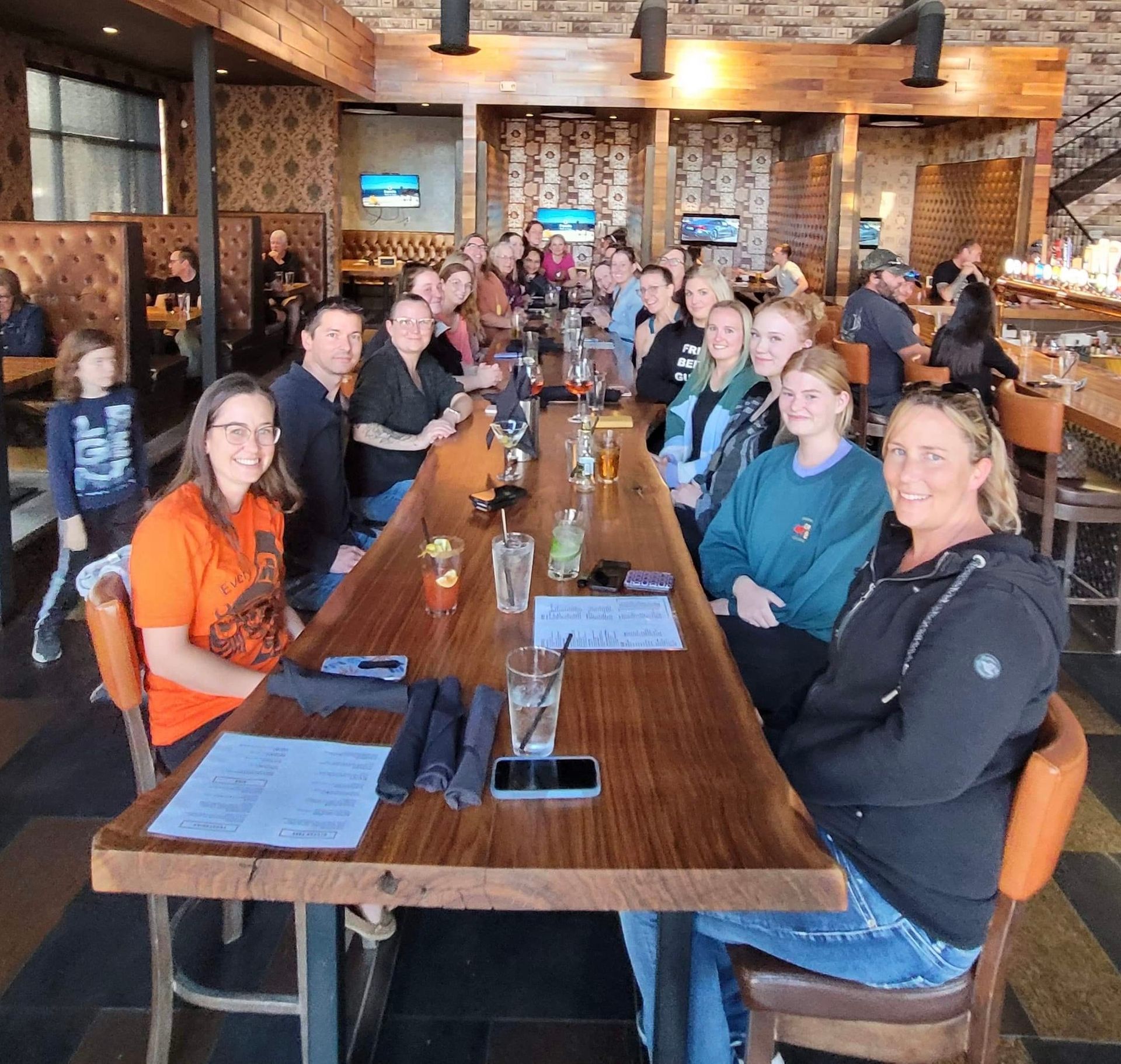 A group of people are sitting at a long table in a restaurant