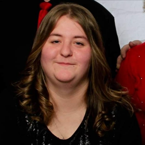 A woman in a black shirt and red tie smiles for the camera