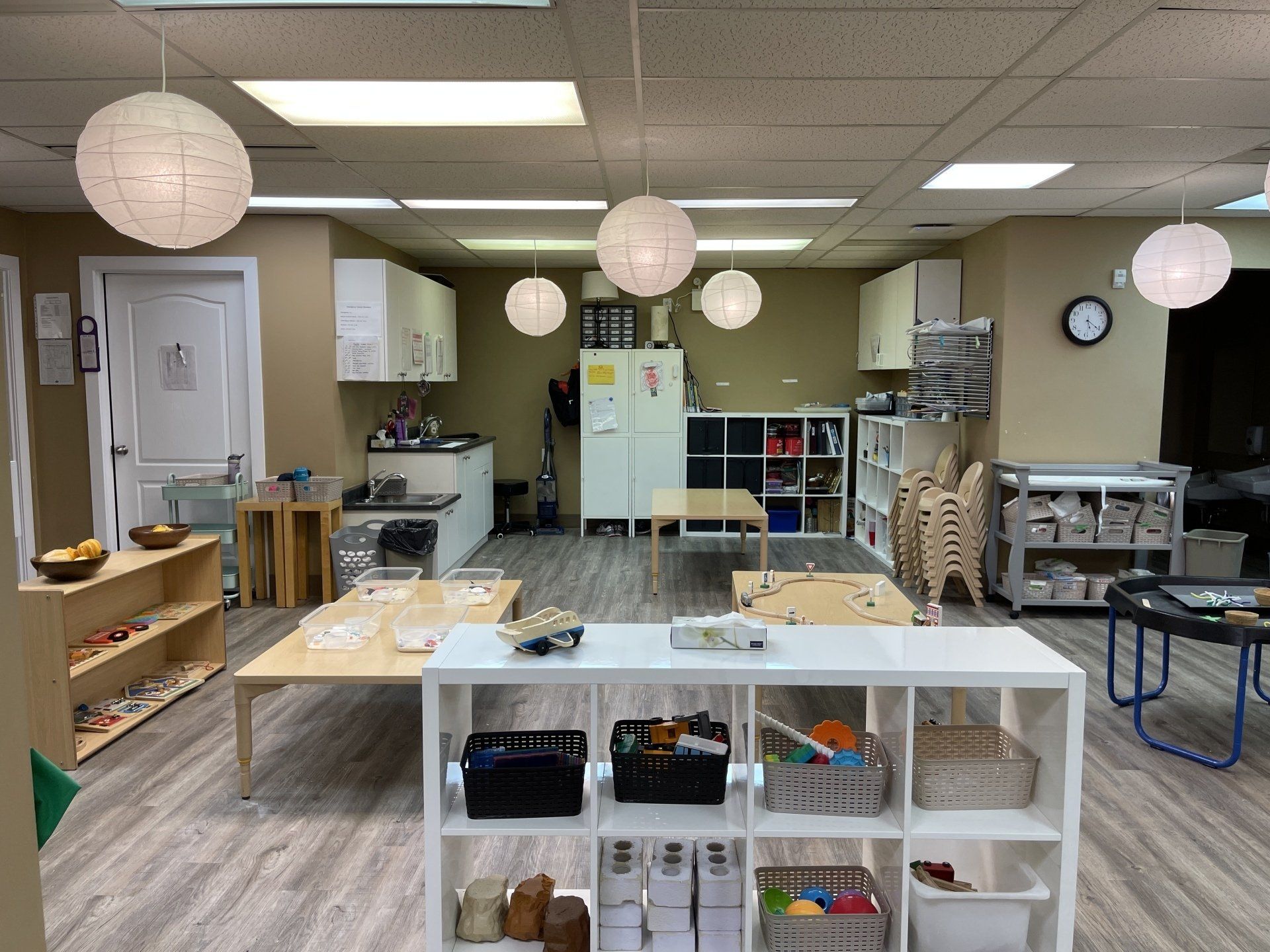 A large room with tables , shelves , and a refrigerator.