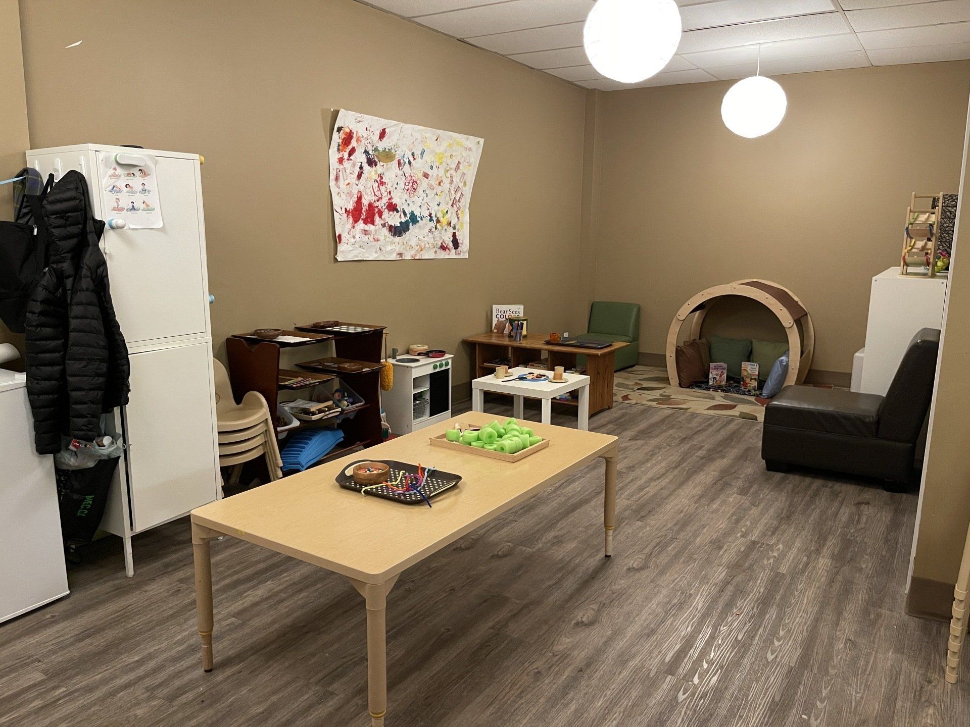 A living room with a table , chairs , and a refrigerator.