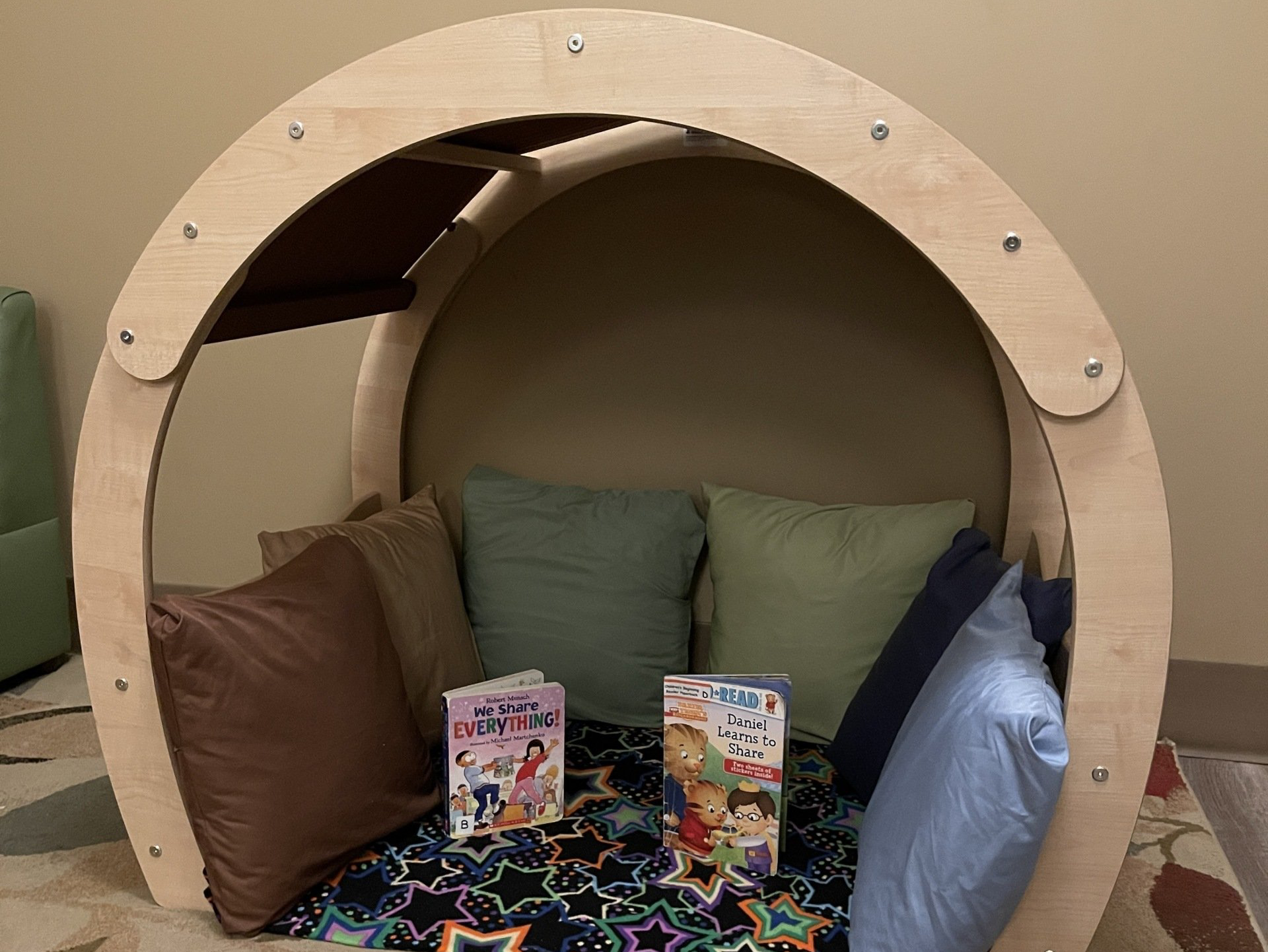 A wooden circle with pillows and books on the floor