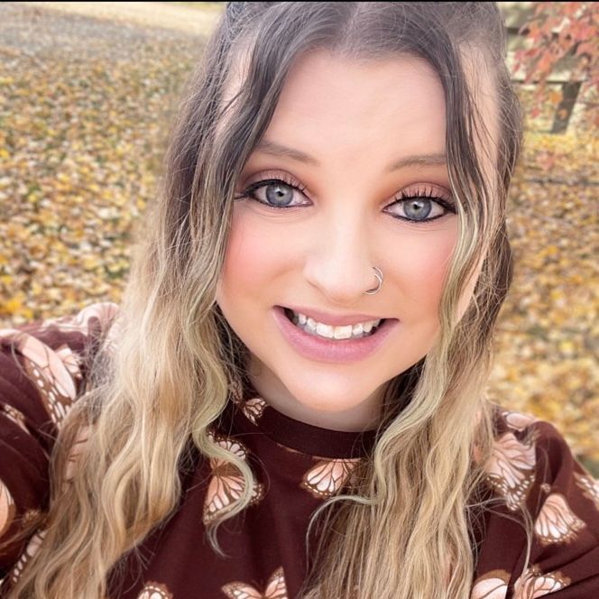 A woman wearing a brown shirt with butterflies on it is smiling