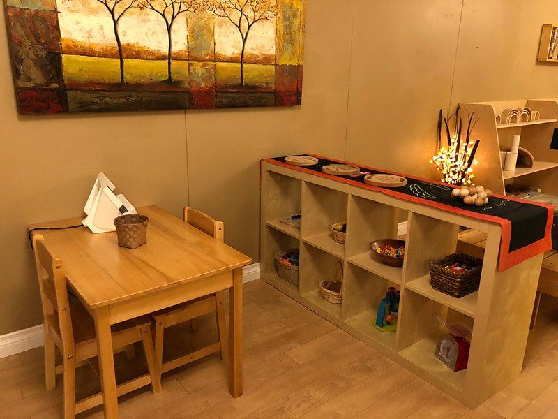 A room with a table and chairs and a painting on the wall.