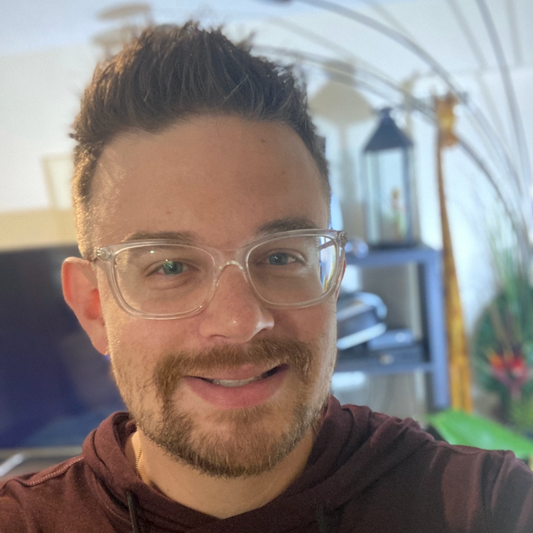 A man with glasses and a beard is smiling for the camera.