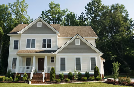 Two-story gray house with white trim, front porch, and landscaped yard on a sunny day