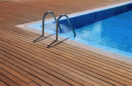 Pool ladder beside blue swimming pool on a wooden deck