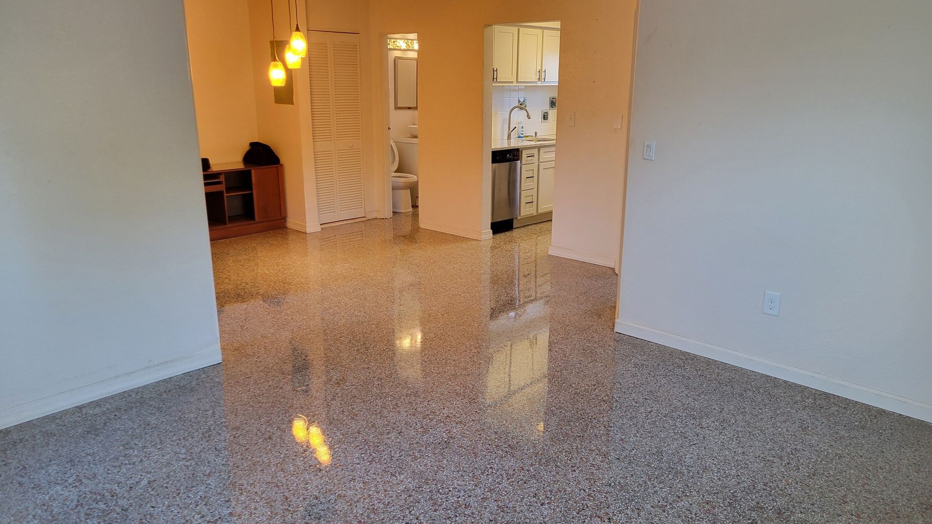 Empty room with polished concrete floor, doorways to other rooms, and neutral walls.