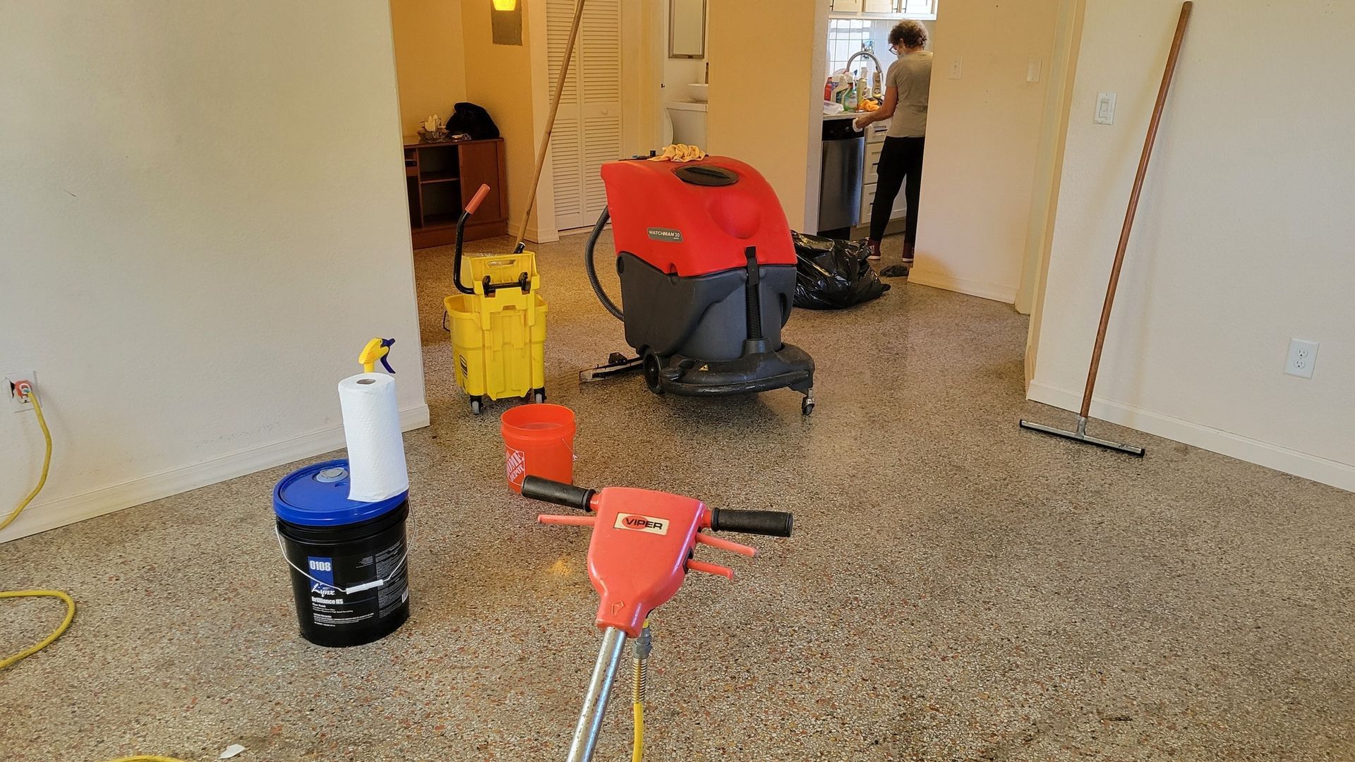 Cleaning a terrazzo floor with machinery. Tools and person visible in an interior space.