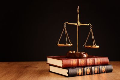 Golden scales on stacked law books against a dark background
