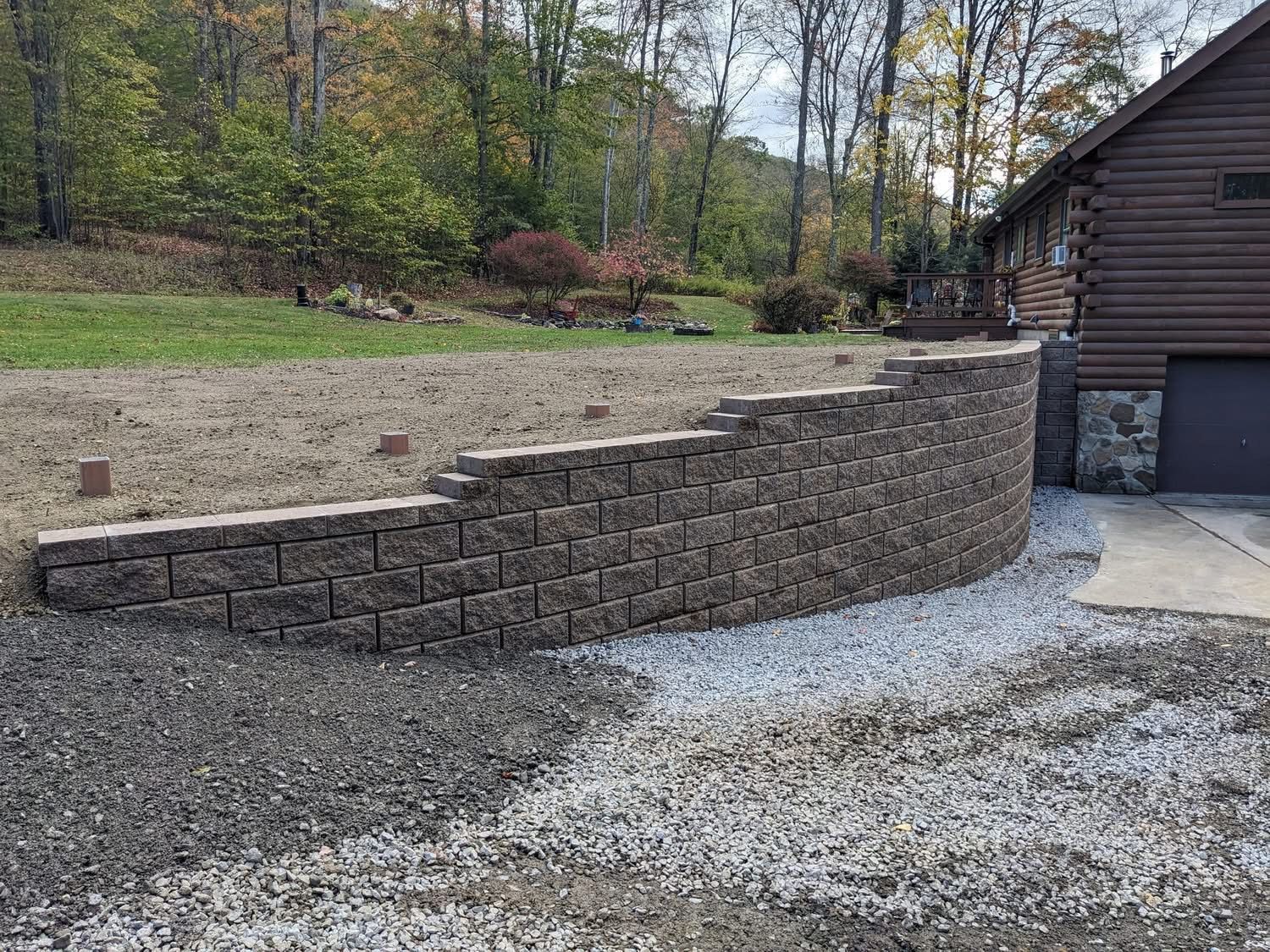 Retaining wall made of brown bricks, next to a driveway and grassy yard.