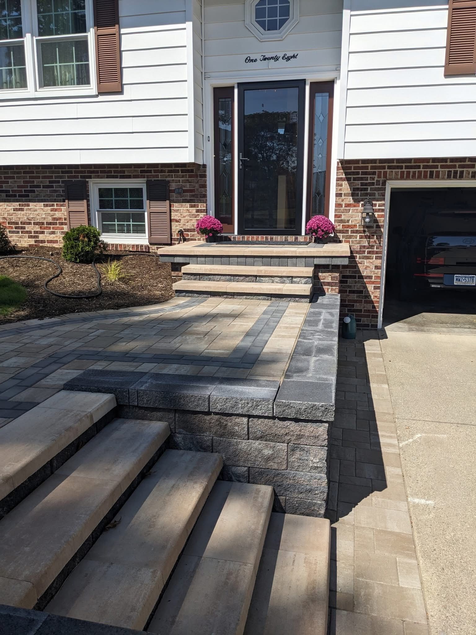 House exterior with paver steps and walkway leading to front door with flower pots.