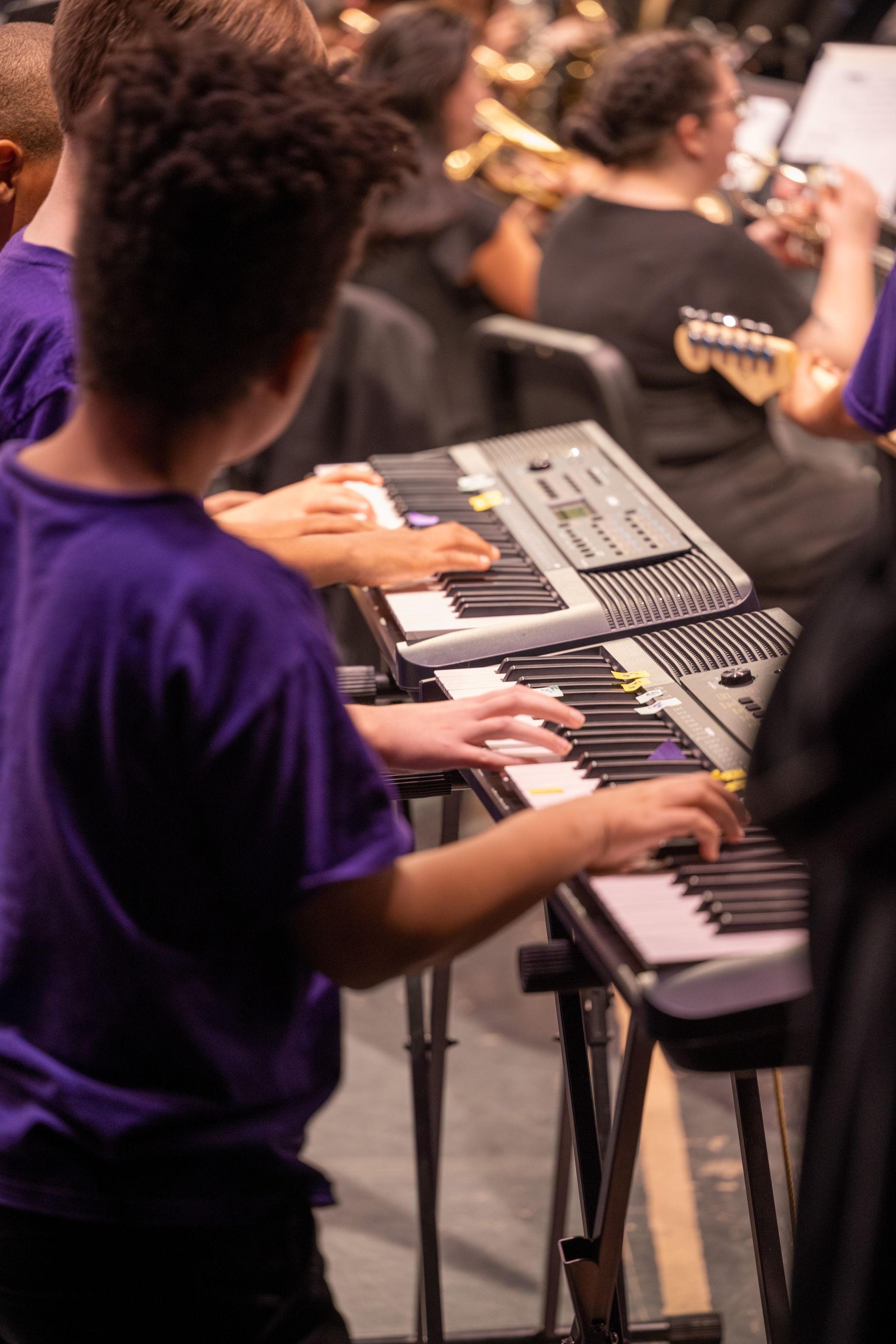 People playing electronic keyboards in a music rehearsal room