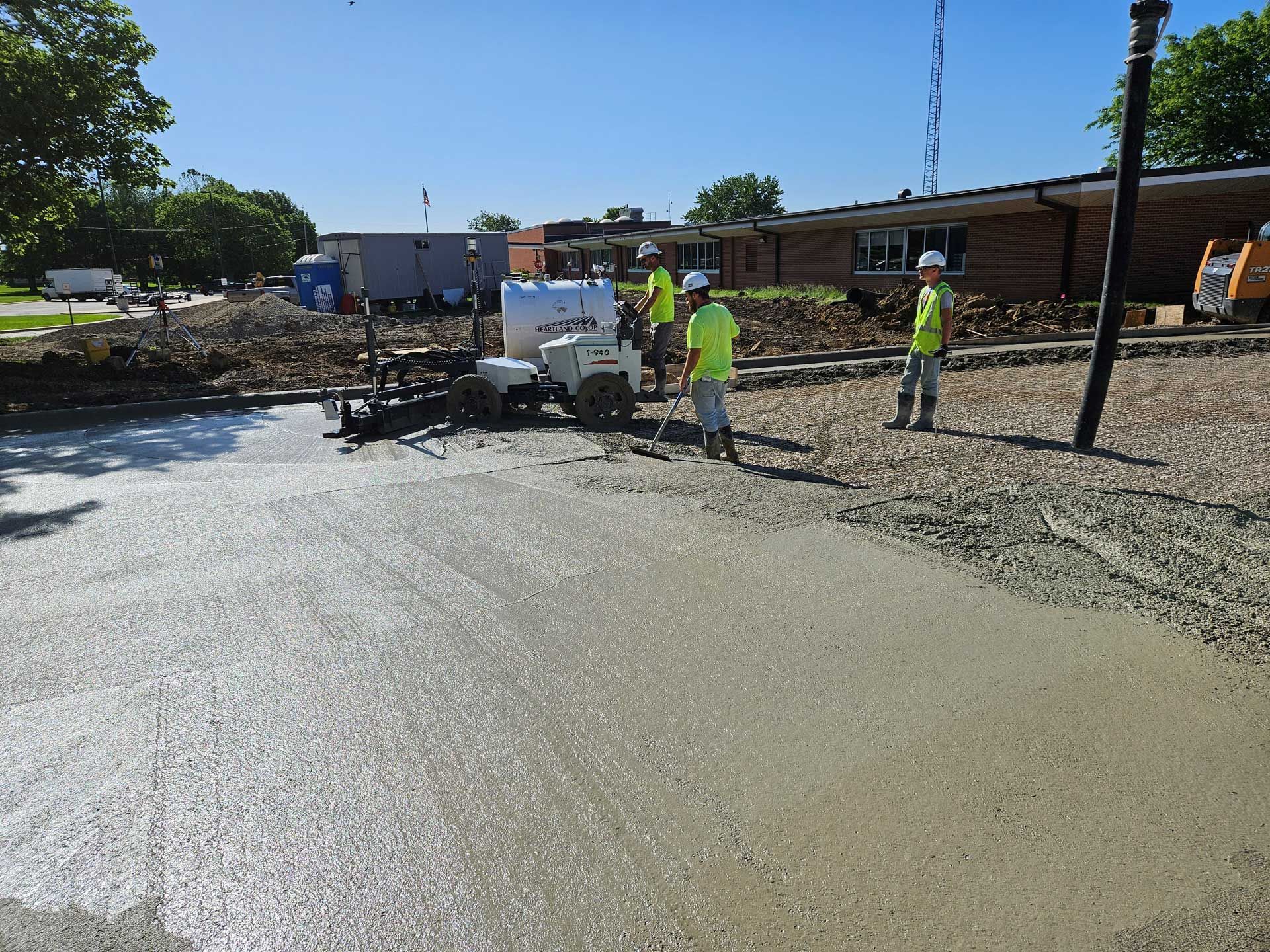 A group of construction workers are working on a concrete driveway