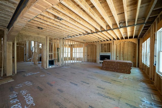 Unfinished room under construction with exposed wooden framing, beams, and windows along the right wall.