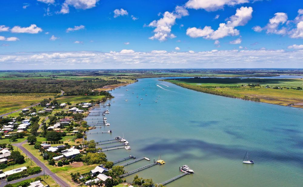 An Aerial View of a River Surrounded by Houses and Trees — Anthony Cameron Electrical & Solar in Bundaberg, QLD