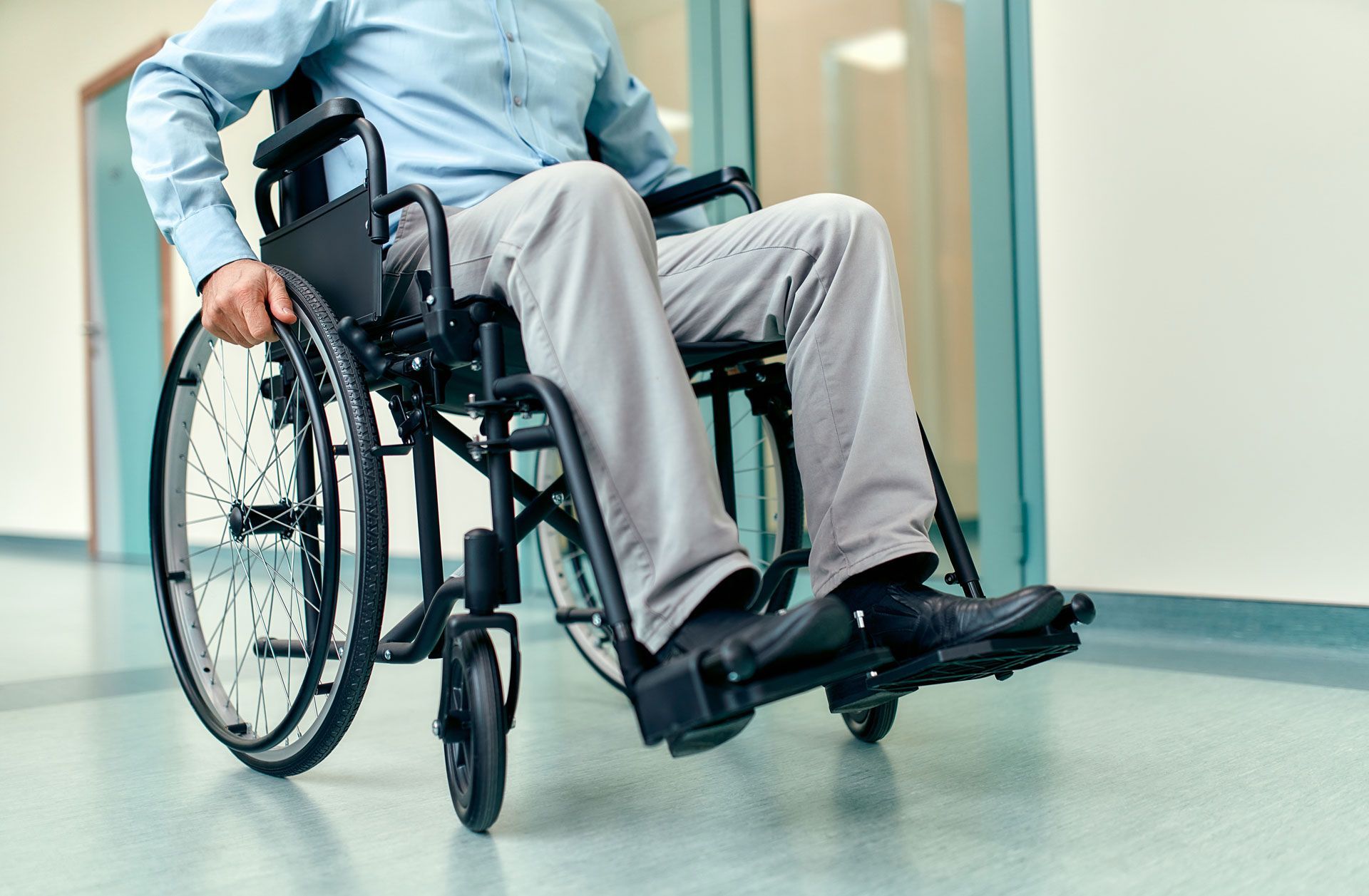 A man is sitting in a wheelchair in a hospital hallway.