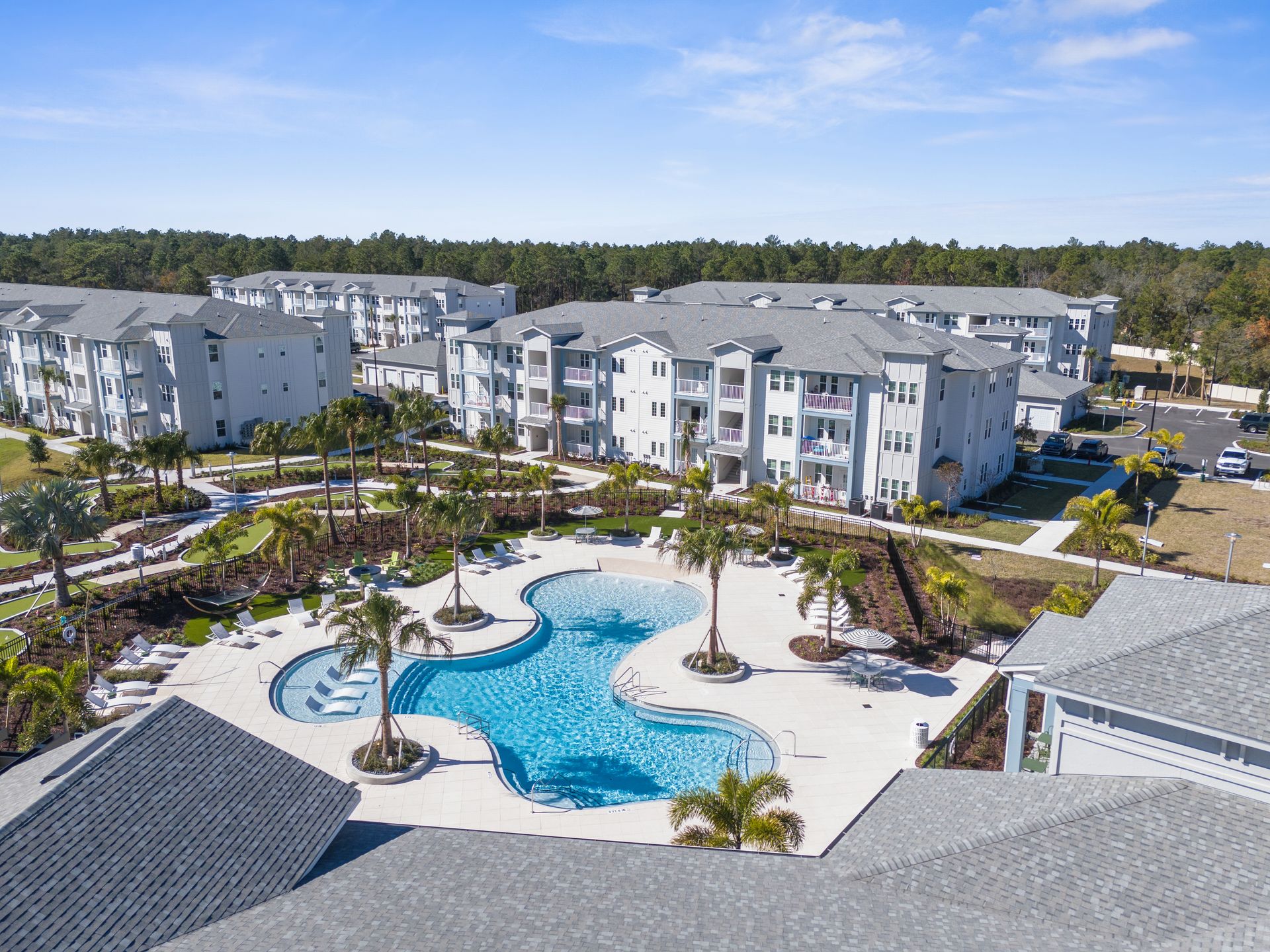 Aerial view of apartment complex with pool and palm trees.