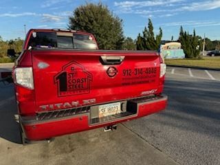 Red Nissan Titan pickup truck with company logo on the tailgate, parked outdoors.