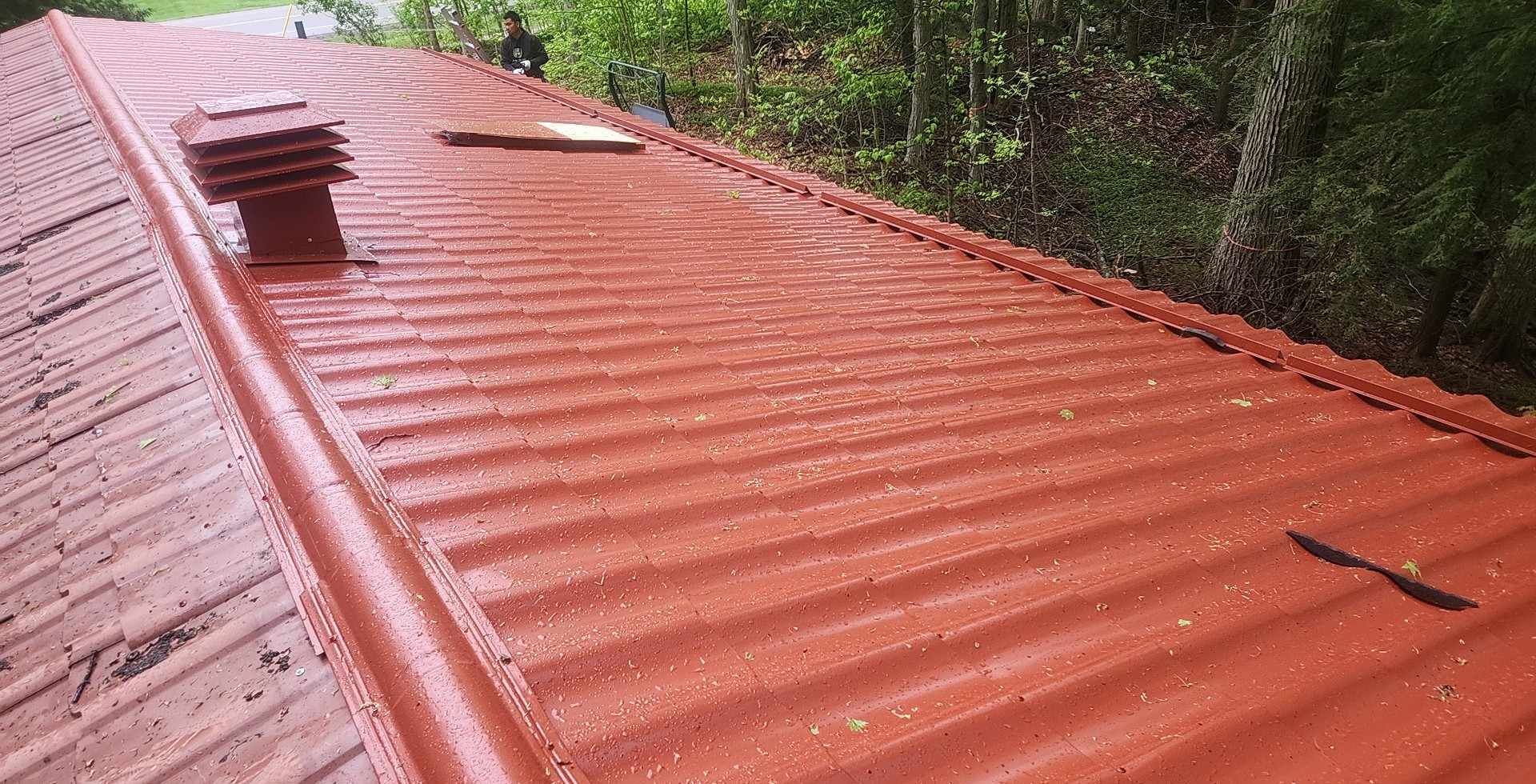 A close up of a red roof with trees in the background.