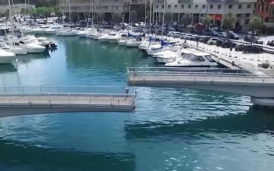A bridge over a body of water with boats docked in the background.