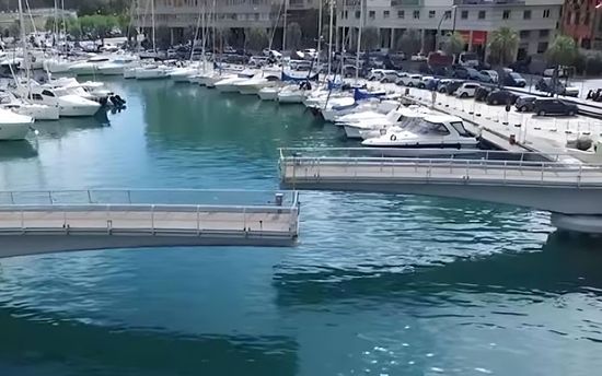 A bridge over a body of water with boats docked in the background.