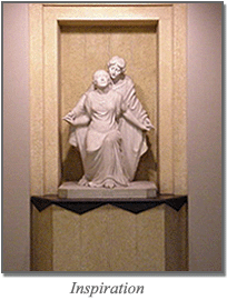 Stone statue of two figures in a niche, with “Inspiration” written below