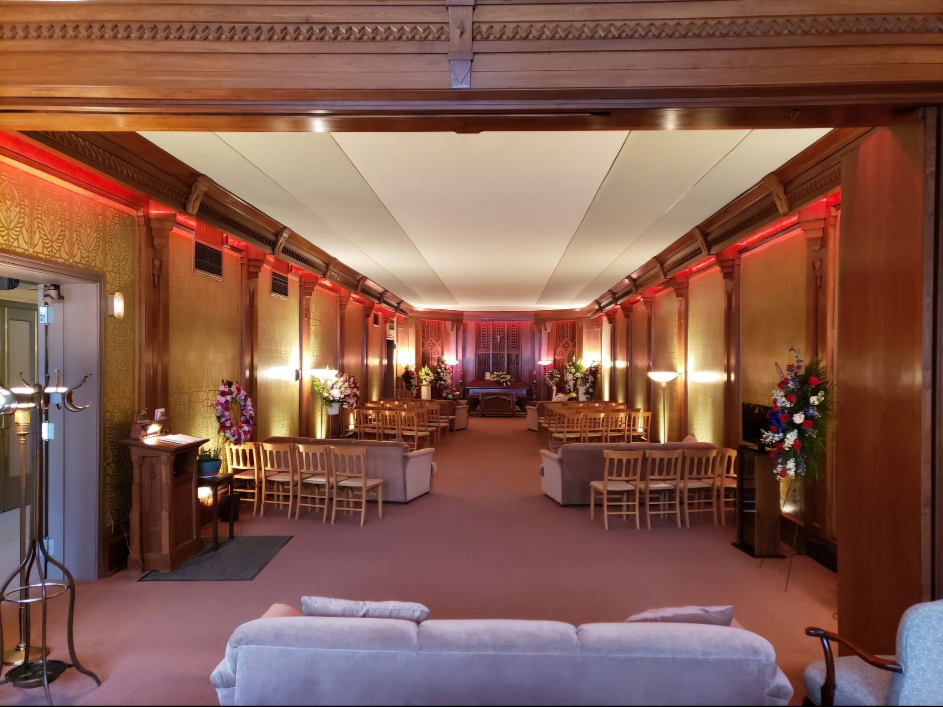 Elegant banquet hall with warm red lighting, rows of tables, and a small stage at the far end