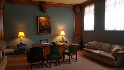 Cozy living room with a dining table, two lamps, wall art, and a beige sofa by large windows.