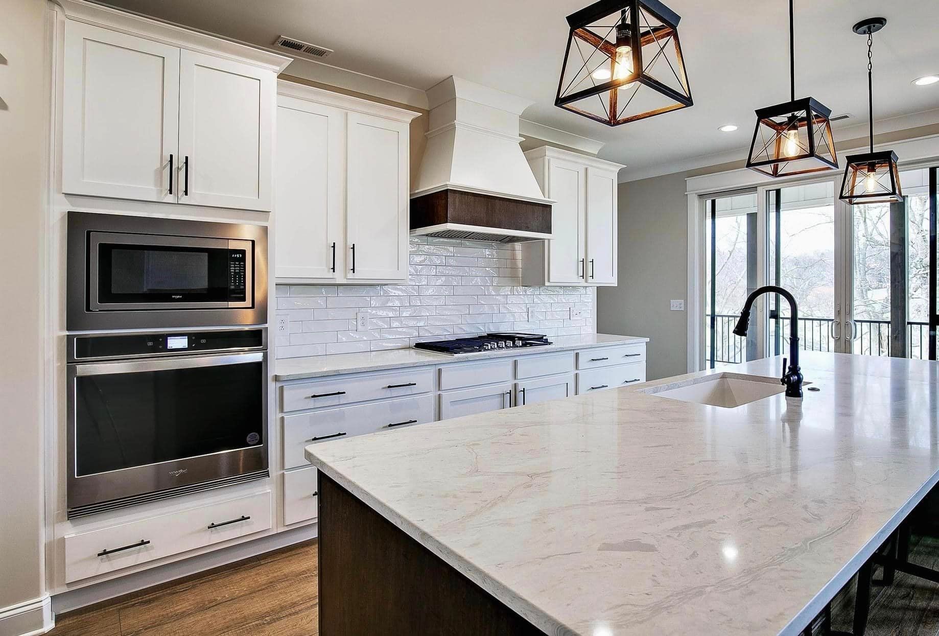 A kitchen with wooden cabinets and hardwood floors and a large island in the middle.