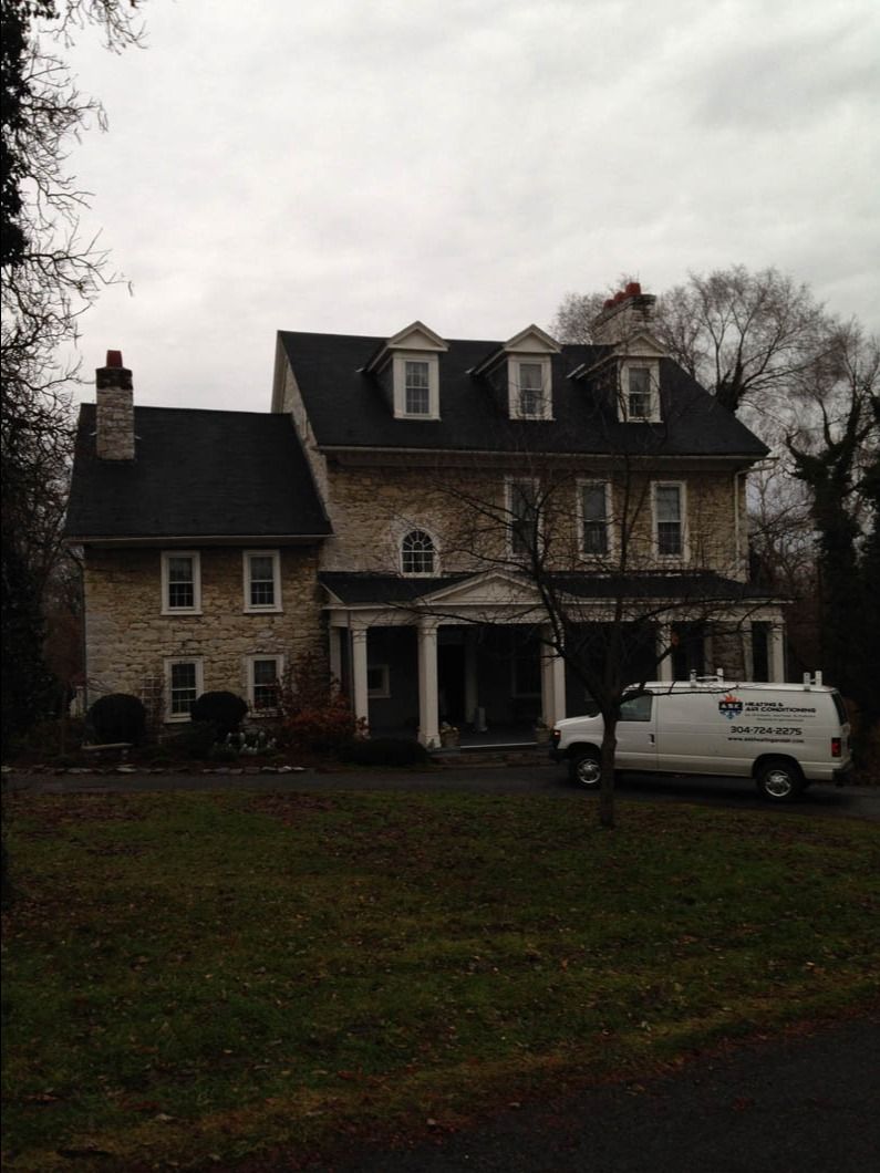 Stone house with dormer windows and a white van parked in front on a cloudy day