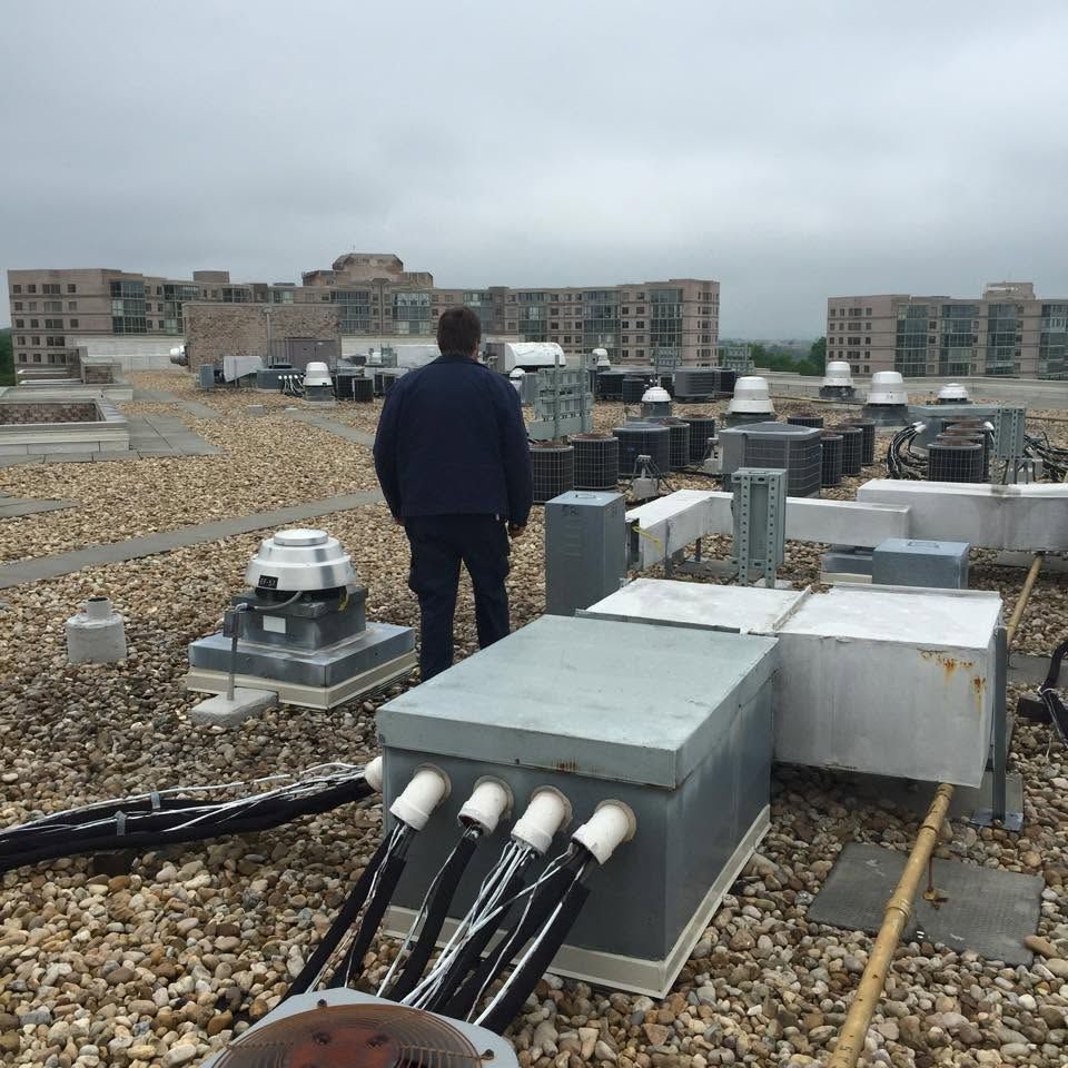 Person standing on a gravel rooftop with HVAC units and apartment buildings in the background