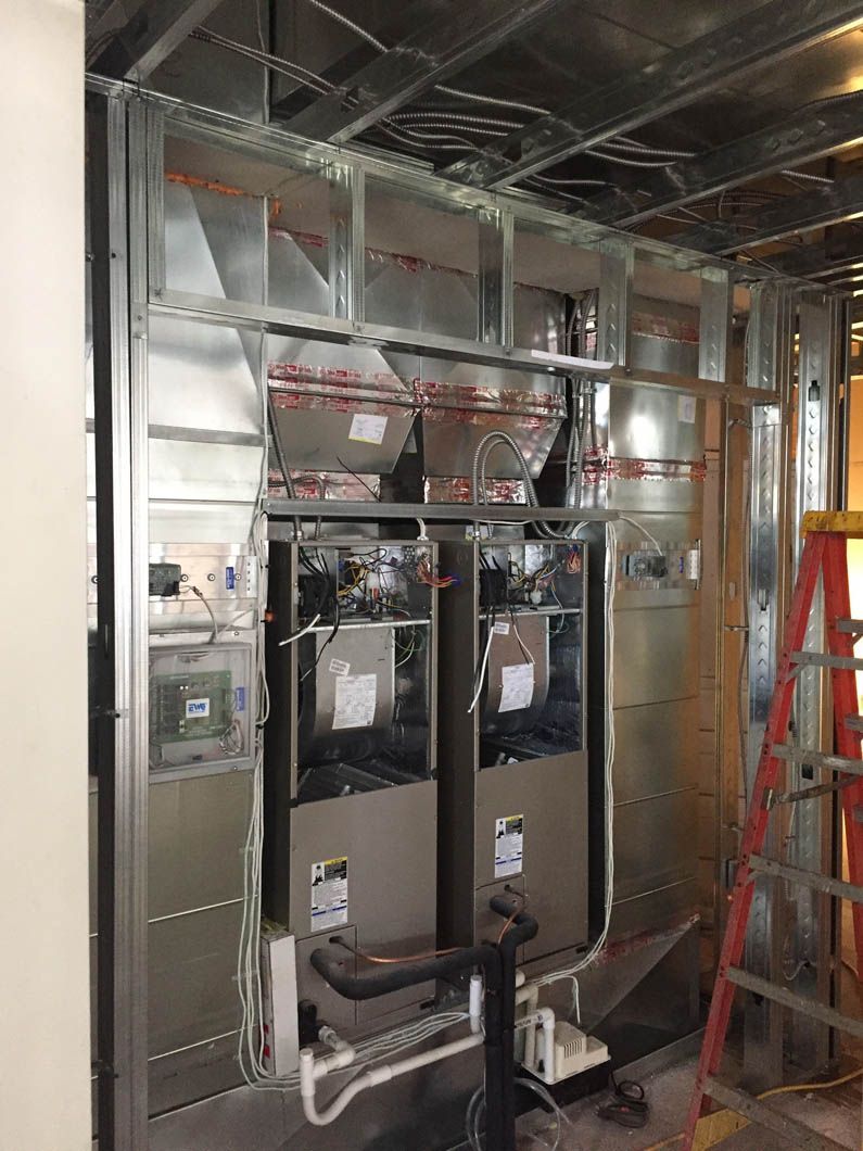 Interior wall framing with HVAC ducts and two installed units in a construction site