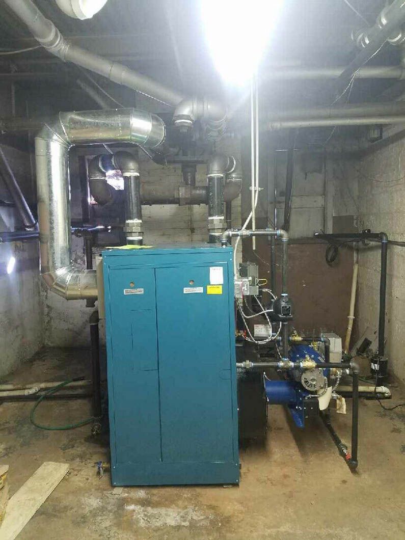 Industrial boiler room with blue equipment, metal pipes, and concrete walls.
