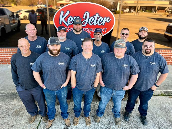 A group of men are posing for a picture in front of a kee jeter sign.