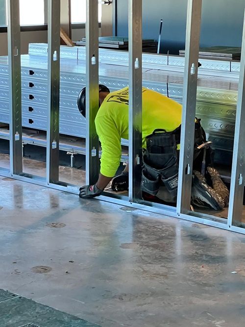 A man in a yellow shirt is working on a wall