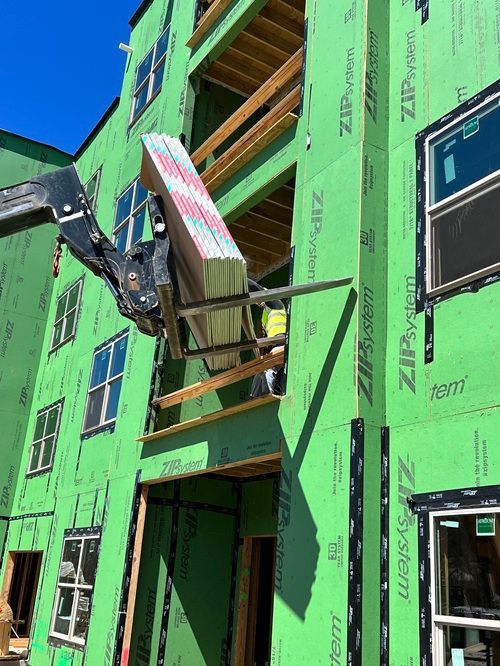 A crane is lifting a large piece of foam into a building under construction.