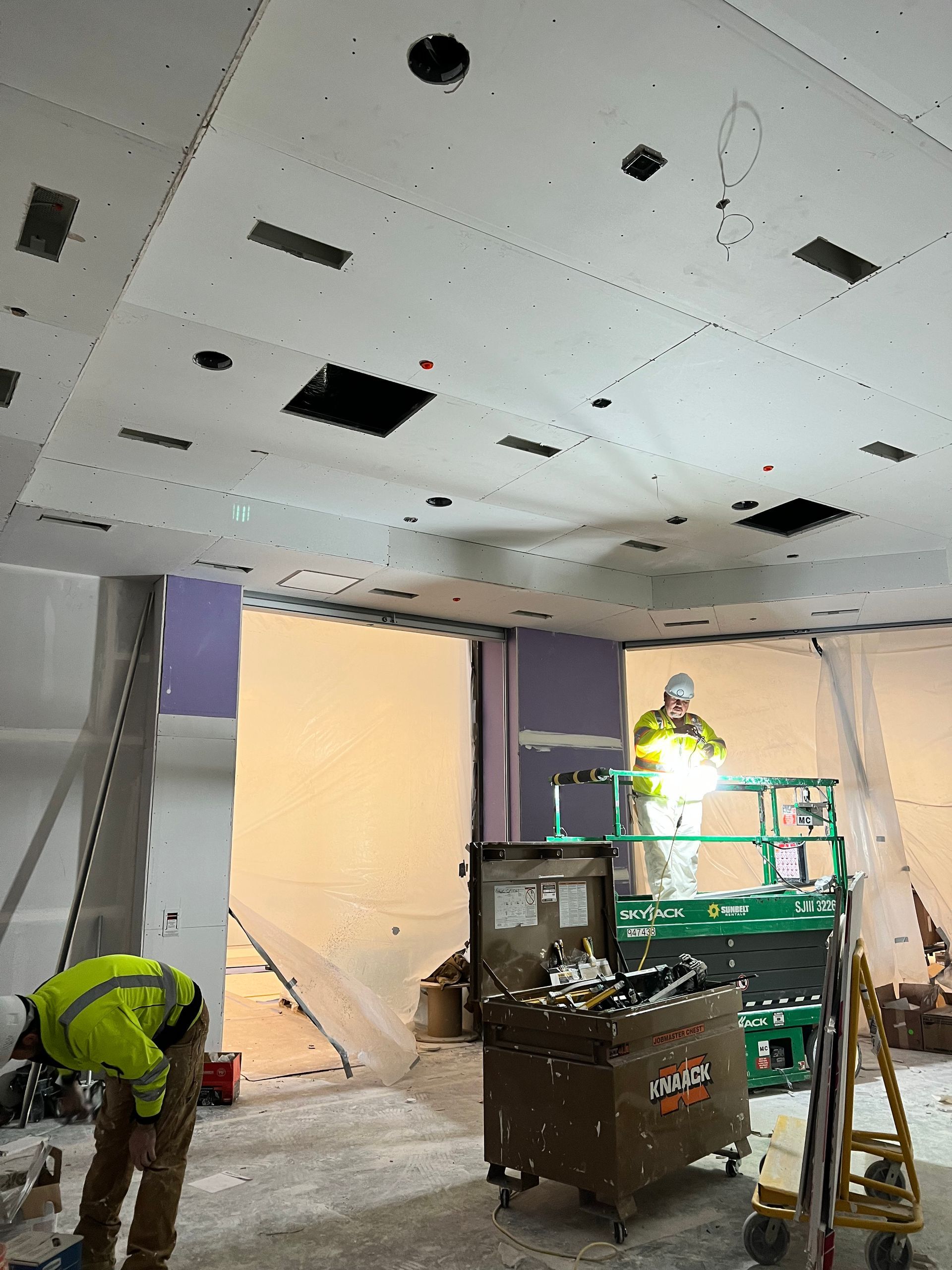 A man is working on the ceiling of a building.