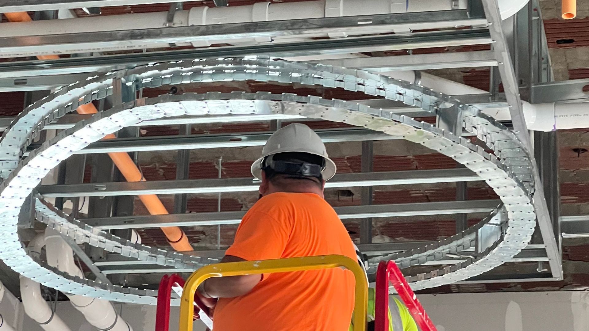 A man is standing on a ladder in a building under construction.
