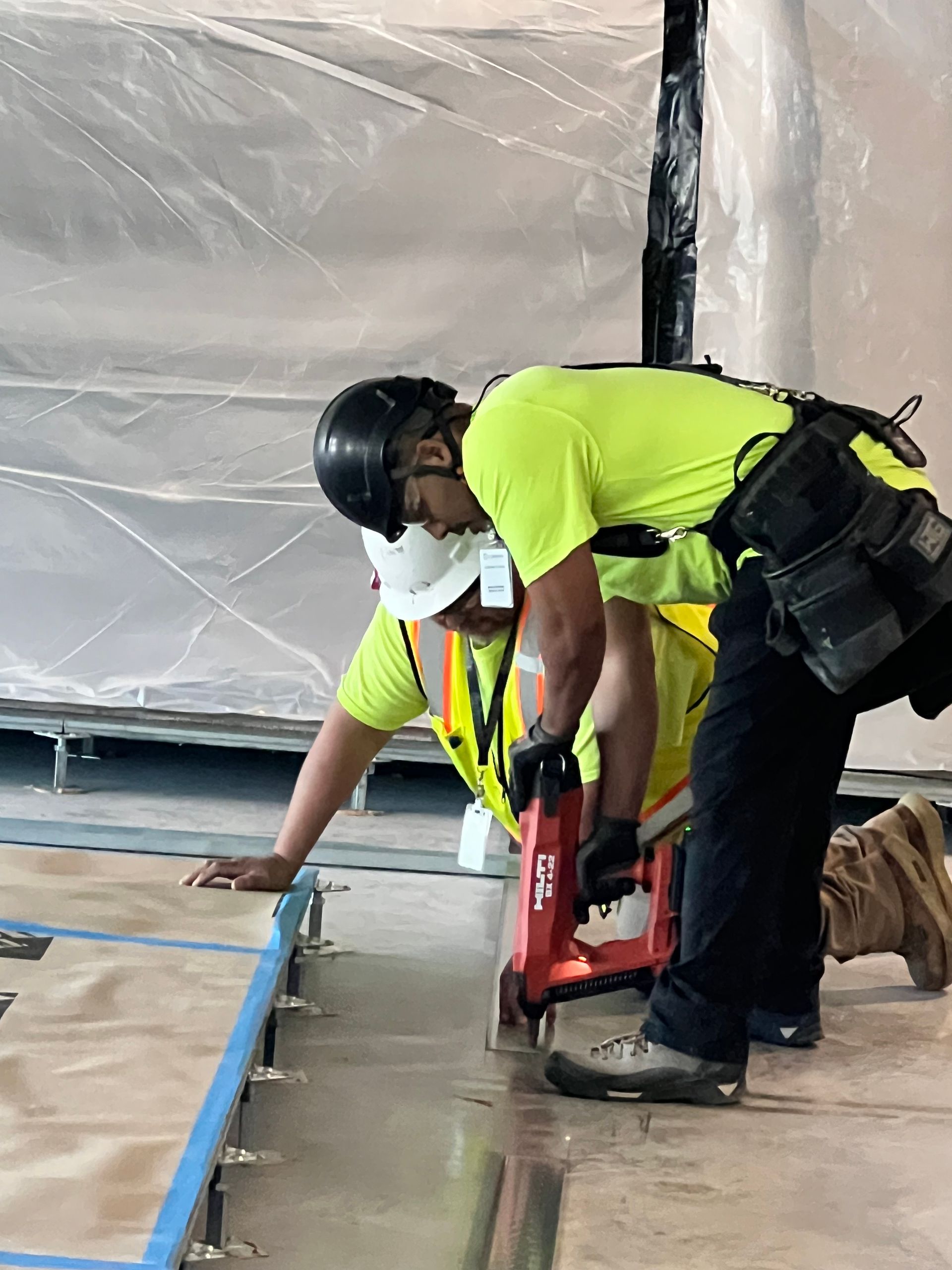 Two construction workers wearing hard hats and safety vests are working on a project.