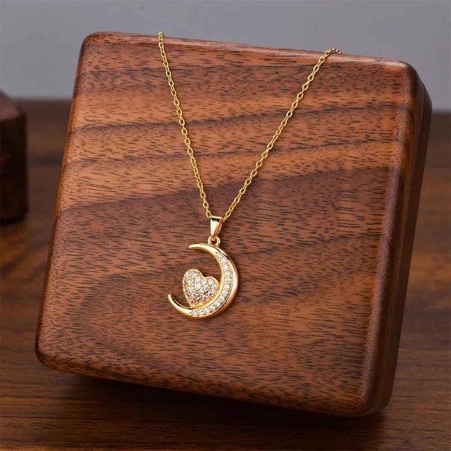 Collar dorado con colgante de luna creciente, exhibido en un soporte de madera