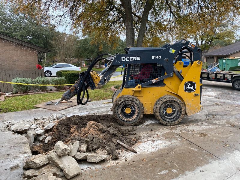 Skid steer breaking up an old concrete driveway before replacement