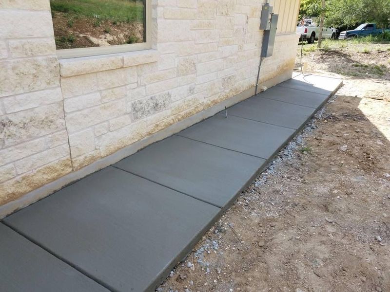 New concrete sidewalk along a stone home