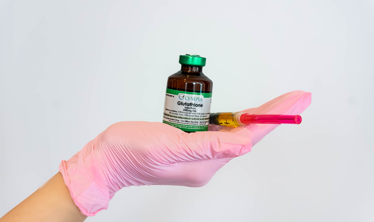 Hand in pink glove holding a vial of medicine and a syringe.
