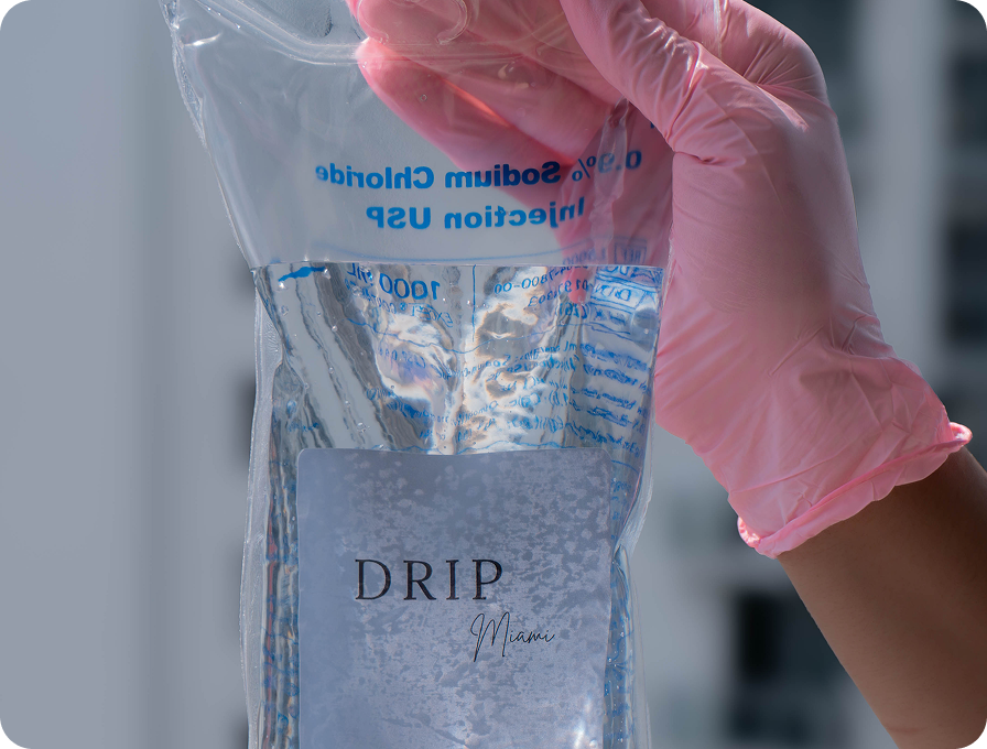Person in pink gloves holding a saline IV bag labeled 