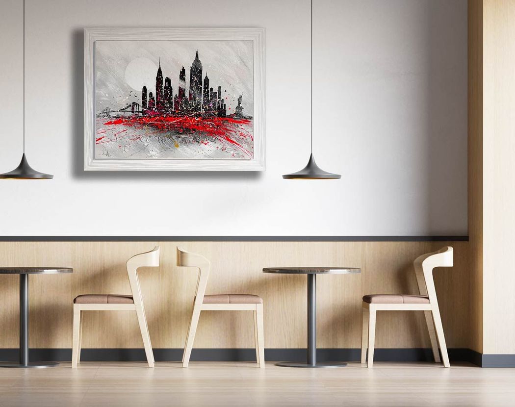Caffè moderno e minimalista con sedie bianche, tavolini, lampade a sospensione e opere d'arte astratte raffiguranti la città alle pareti.