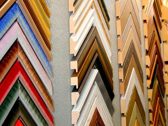 File di angoli per cornici colorati impilati verticalmente, che mostrano diverse finiture in legno e metallo.