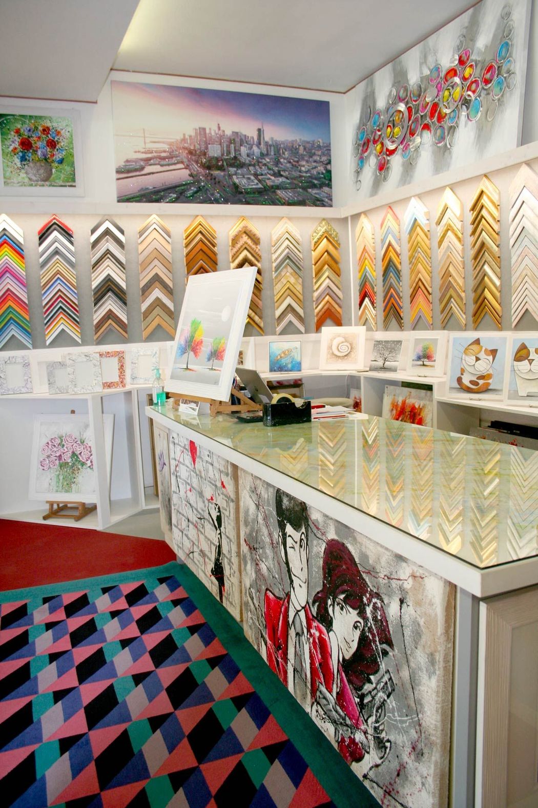 Interno colorato di una galleria d'arte con quadri incorniciati, pareti decorate e un tappeto geometrico.