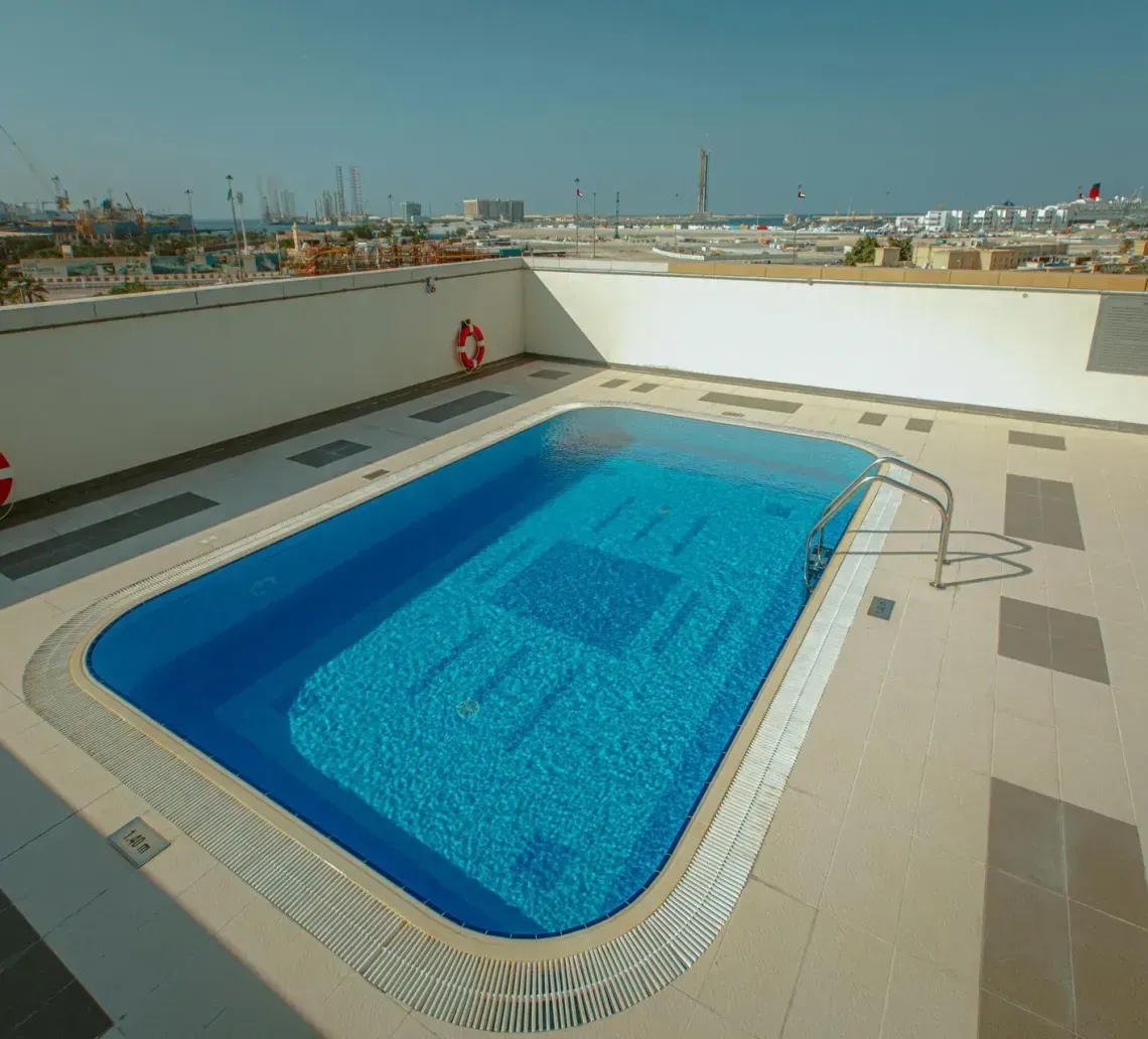 Rooftop swimming pool with bright blue water and white deck overlooking a city skyline